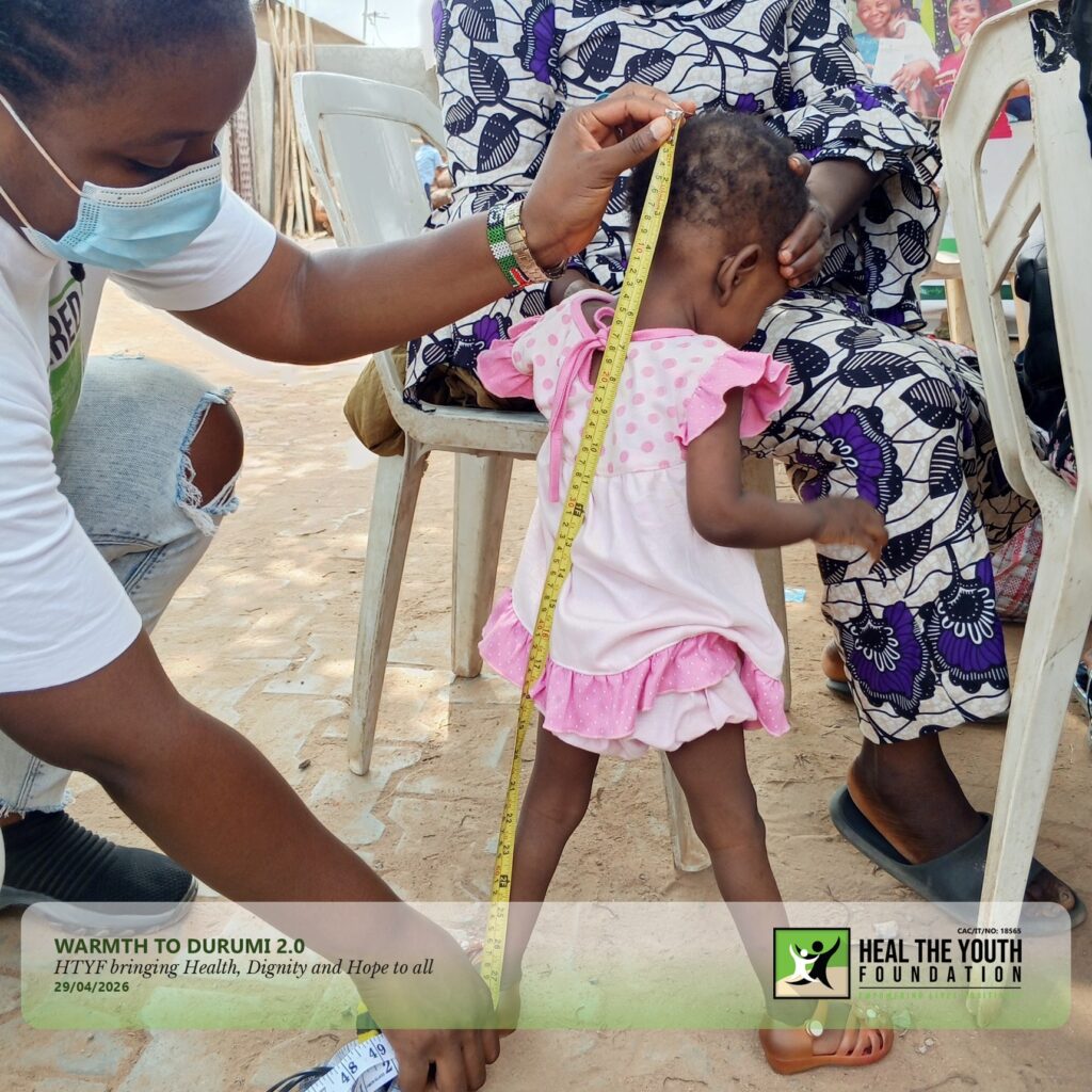 A photo of the volunteer assessing the height of a child with a tape.